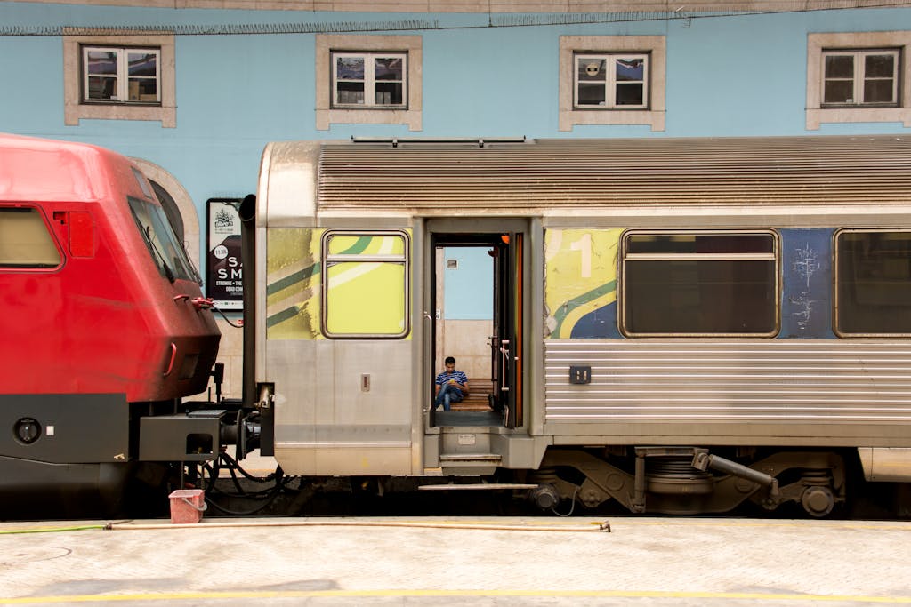 A red and silver train connected at a station with a person inside, showcasing urban transport.