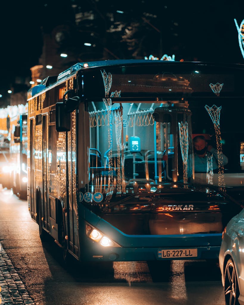 Buses adorn Kutaisi street at night, capturing urban transportation with festive lights.